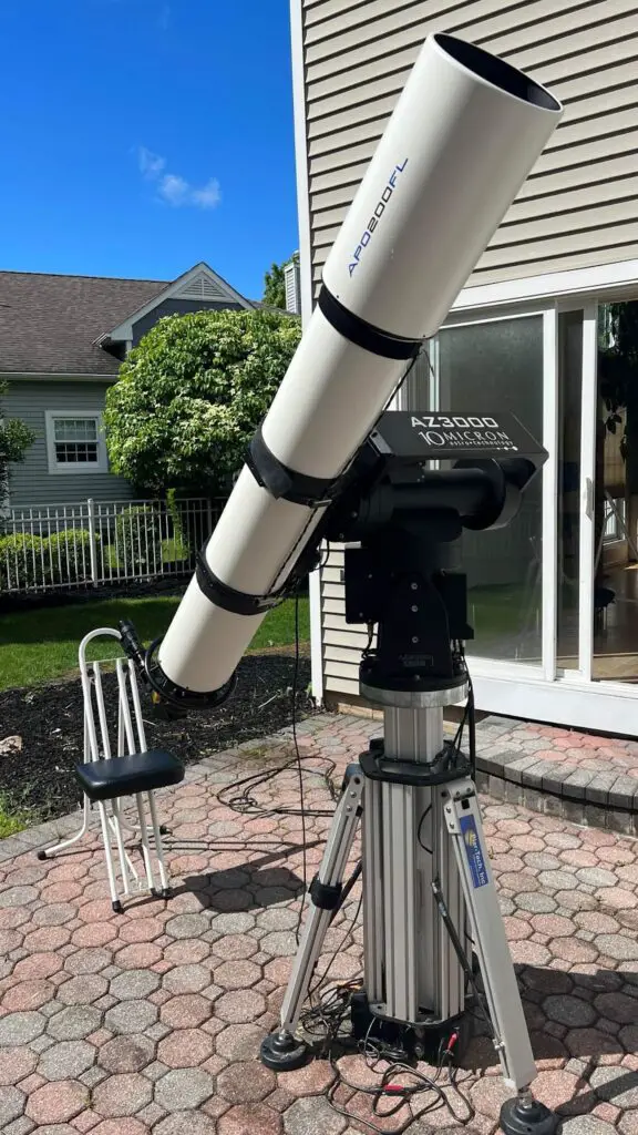 White telescope on heavy mount in backyard. 